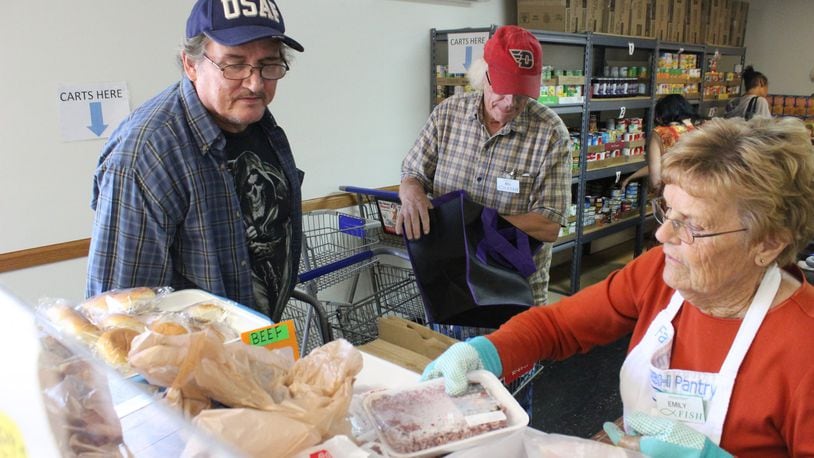 Veteran Dwight Martin Jr. (left) selects from the frozen meat selection at FISH Food Pantry in Fairborn from volunteer Emily Webb (right). FILE
