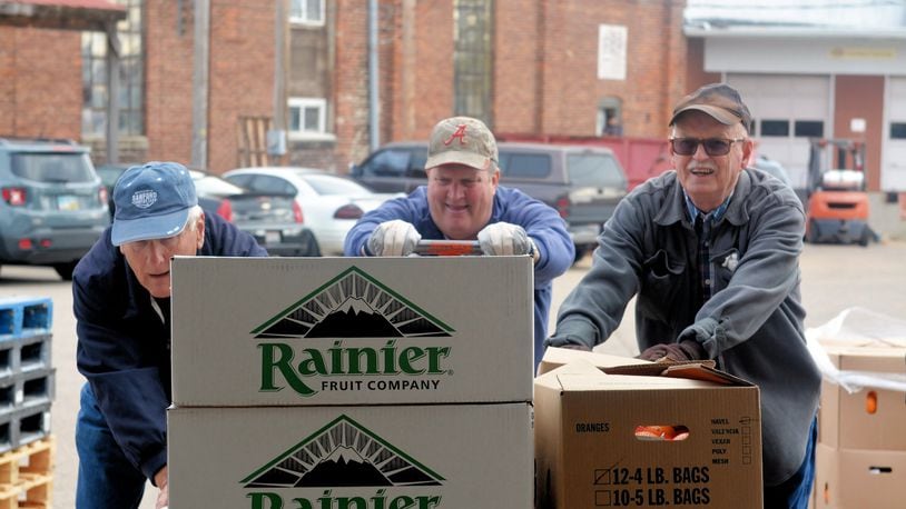 Volunteers bring fruit into the work area as volunteers prepare baskets for the 2015 Christmas Basket project by Tipp City Needy Basket. CONTRIBUTED