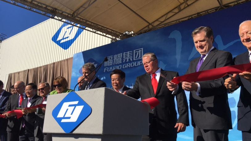 Joined by U.S. Sen. Sherrod Brown to his right, and Fuyao Glass America supervisor Michael Fullenkamp to his left, Fuyao Global Chairman Cho Tak Wong helped cut the ribbon at Fuyao’s Moraine plant in October 2016 at the company’s grand opening celebration. THOMAS GNAU/STAFF