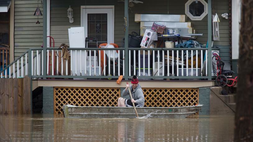 A man paddles his boat alongside a home in the East End along the Ohio River, Saturday, Feb. 24, 2018, in Cincinnati.  Forecasters expected the Ohio River could reach levels not seen since the region's deadly 1997 floods. (Liz Dufour/The Cincinnati Enquirer via AP)