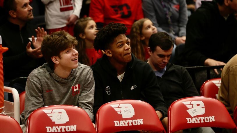 Jacob Theodosiou, left, sits behind the Dayton bench with teammate Damarius Owens on March 5, 2022, at UD Arena during a game against Davidson. David Jablonski/Staff