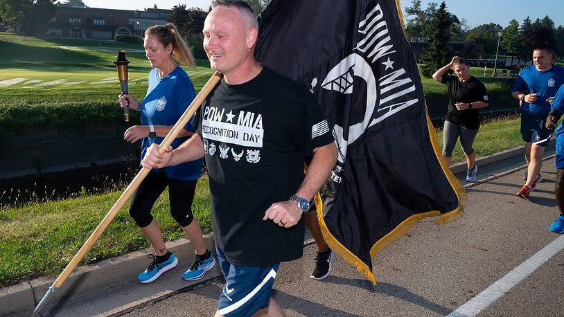 Chief Master Sgt. Shawn Plowman, 88th Diagnostics and Therapeutics Squadron, carries the POW/MIA Flag while Chief Master Sgt. Lindsey Wolf, Air Force Materiel Command command paralegal, holds up the torch as they lead a Wright-Patterson Chiefs Group delegation on the annual POW/MIA run Sept. 17. Runners delivered the torch and flag to the POW/MIA Recognition Day wreath-laying ceremony at Wright-Patterson Air Force Base. U.S. AIR FORCE PHOTO/R.J. ORIEZ