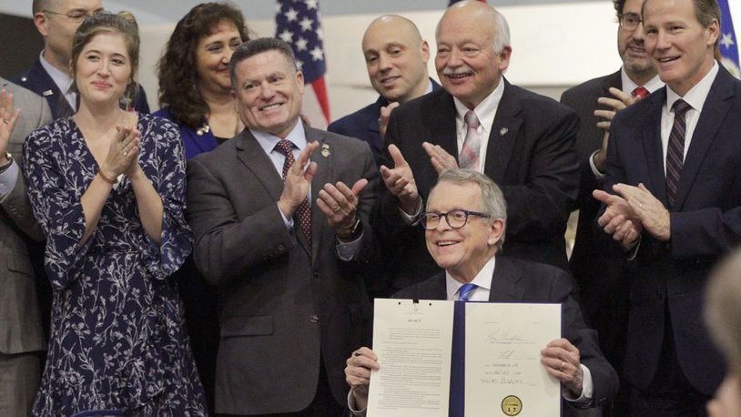 Gov. Mike DeWine signed Ohio Senate Bill 7 in January 2020 during a ceremony at the National Museum of the U.S. Air Force. The bill mandates state occupational licensing agencies issue temporary licenses and certificates to members of the military and spouses who are licensed in another jurisdiction and have moved to Ohio for military duty. From left to right are Brianna McKinnon, a military spouse and special education teacher, Rep. Rick Perales, Sen. Bob Hackett and Lt. Gov. Jon Husted. LISA POWELL / STAFF