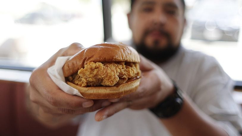 Randy Estrada holds up his chicken sandwiches at a Popeyes, Thursday, Aug. 22, 2019, in Kyle, Texas.