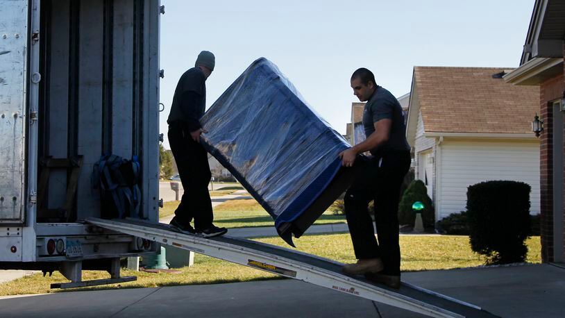 Chris Cox. left, and Anthony Pearce, employees of Two Men and a Truck Moving and Storage, load belongings of a Huber Heights household being moved to Virginia. CHRIS STEWART / STAFF