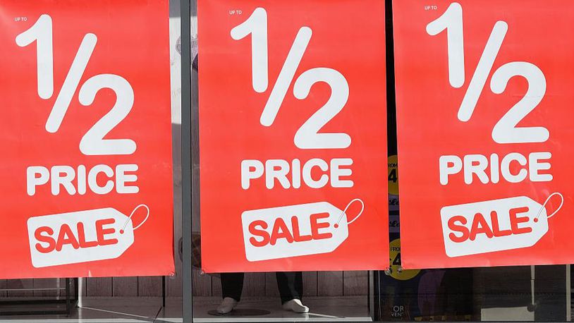 Posters advertising a sale are displayed in a shop window (Photo by Ian Forsyth/Getty Images)