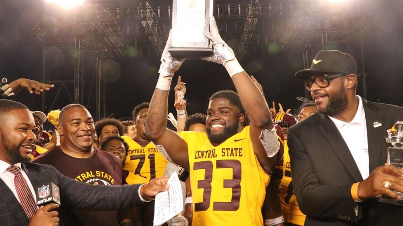 Central State's Jalil Lenore (33) and head coach Kevin Porter accept Black College Football Hall of Fame Classic trophy from Central State Hall of Famer Erik Williams on Sunday night in Canton. Nick Novy/Central State Athletics