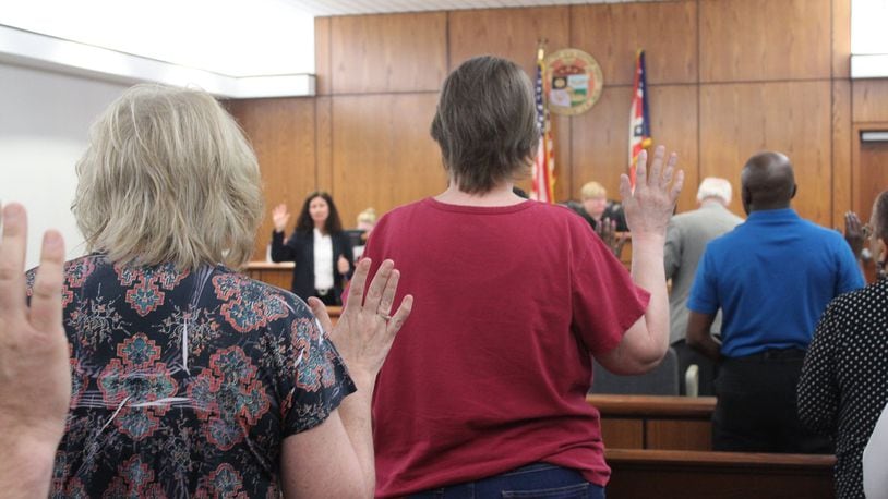 Visitors to Dayton Municipal Court on Friday raise their right hands to swear they will tell the truth in testimony about eviction cases. CORNELIUS FROLIK / STAFF
