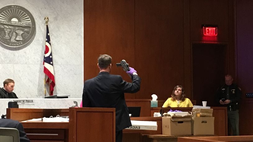Assistant Warren County Prosecutor Travis Vieux holds the alleged murder weapon, an AK-47 pistol above his head, during testimony Wednesday in the Christmas Day 2016 murder trial.