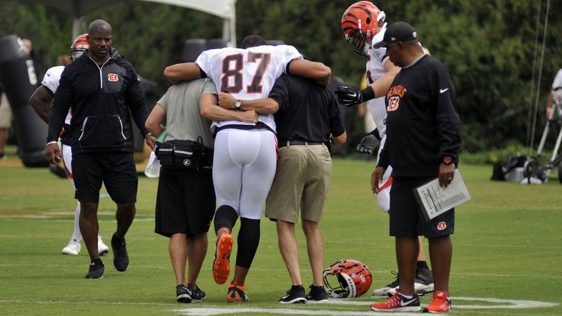 Cincinnati Bengals tight end C.J. Uzomah is helped off the field by trainers Monday as head coach Marvin Lewis looks on. JAY MORRISON/STAFF