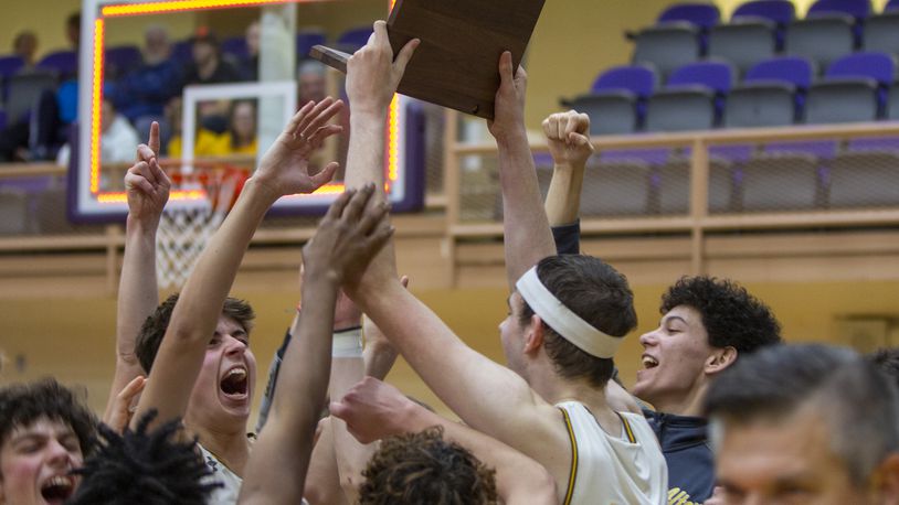 Alter senior Jacob Conner holds up the Division II regional championship trophy and celebrates with his teammates after defeating Cincinnati Woodward 62-49 Saturday at Vandalia Butler. Jeff Gilbert/CONTRIBUTED