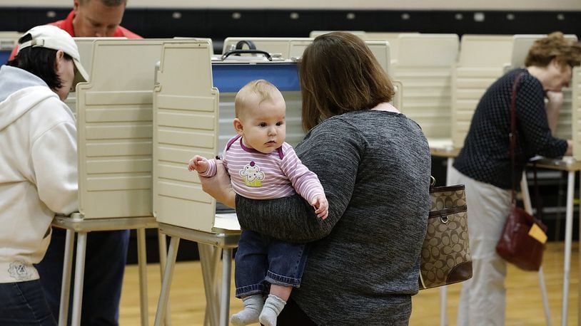 Five-month-old Margaret Russell looks around gymnasium at Tecumseh High School as her mother holds her while casting her vote at the election poll there. Bill Lackey/Staff