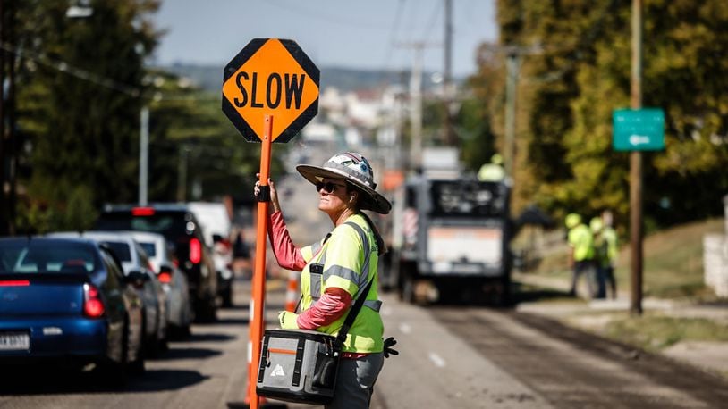 Dana Combs from Jurgensen Asphalt directs traffic on Wayne Avenue on Tuesday October 3, 2023. Crews started repaving a section of Wayne Avenue near the Esther Price store on Tuesday October 3, 2023. JIM NOELKER/STAFF