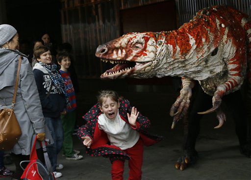Children react as a carnivorous theropod known as the Australovenator dinosaur walks through crowds along the Southbank, in London.