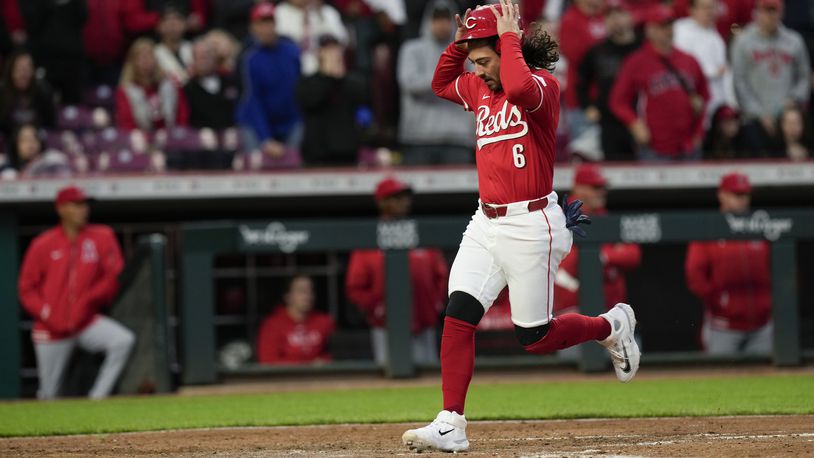 Cincinnati Reds' Jonathan India grabs his helmet as he scores on a single by Stuart Fairchild against the Los Angeles Angels during the fifth inning of a baseball game Saturday, April 20, 2024, in Cincinnati. (AP Photo/Carolyn Kaster)
