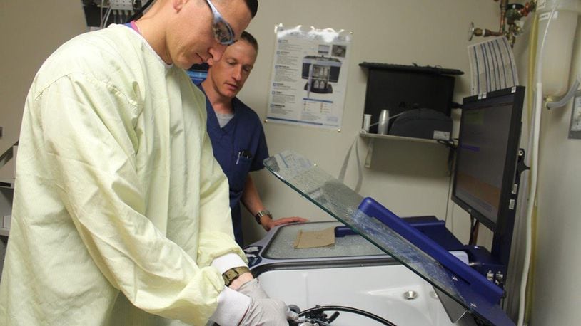 Lt. Col. Tristan Handler, 88th Medical Group chief of gastroenterology, checks medical technician Senior Airman Kaleb Specht, as Specht sanitizes the equipment used in the clinic.