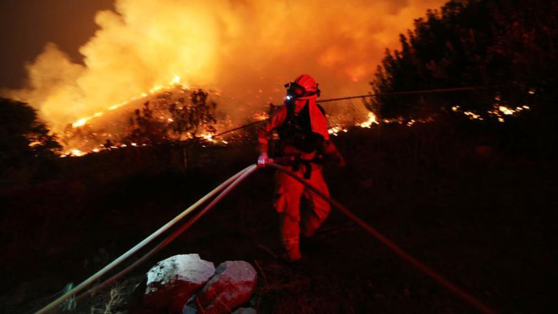 A firefighter works as the Holy Fire burns near homes in Lake Elsinore, California.