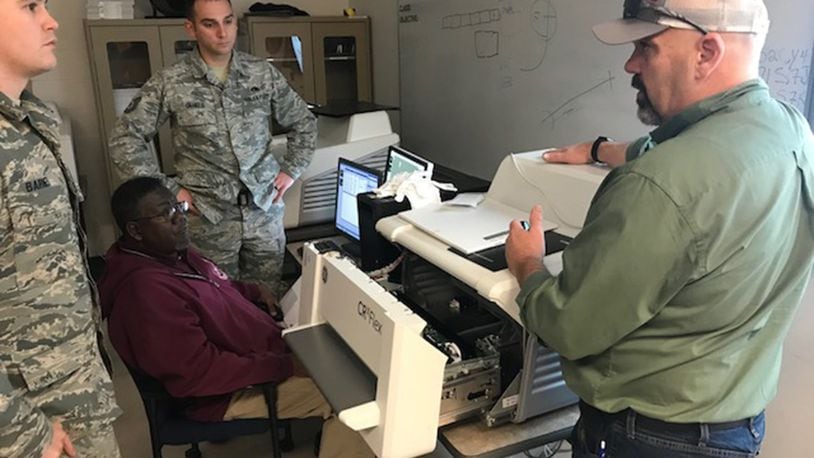 Kevin McClain, contract nondestructive testing instructor, explains how to clear a jammed image scanner from a computed radiography system to visiting Nondestructive Inspection Instructor, Tech. Sgt. Matthew Barnes (left); Tech. Sgt. Clifford Daniels, Military NDI Instructor supervisor (rear); and Bobby Britton, civilian NDI Instructor supervisor (seated) during instructor qualification training held at the 359th Training Squadron Detachment One at Naval Air Station Pensacola, Fla., Jan. 24. New digital technology will replace the X-ray film used by NDI technicians over the next several years and impact every airframe the Air Force flies, saving money, reducing hazardous materials and improving operational capabilities. (Courtesy photo)