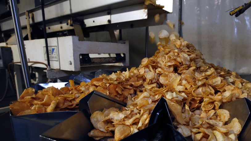 Freshly seasoned potato chips tumble into the bagging machine at Mikesell’s. TY GREENLEES / STAFF