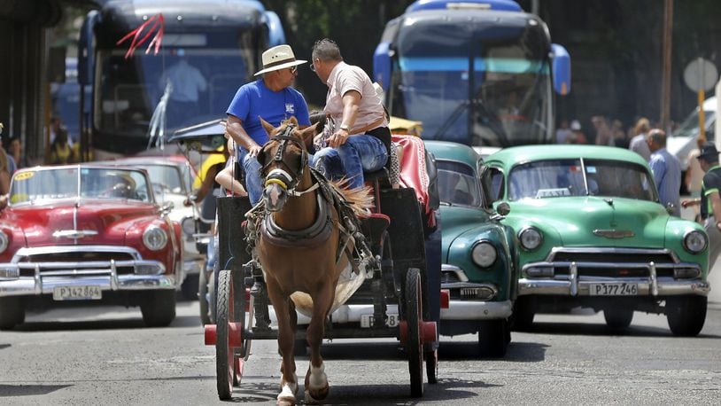 Tourist buses share the road along with vintage American cars and a horse drawn buggy in Havana, Cuba. (Al Diaz/Miami Herald/TNS)