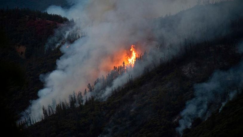 FILE - In this Sunday, July 15, 2018, file photo, Flames from the Ferguson Fire burn down a hillside in unincorporated Mariposa County Calif., near Yosemite National Park. Officials said Saturday, July 21, 2018, that the Ferguson fire is churning northward, sending up smoke that has been obscuring valley views in the park. (AP Photo/Noah Berger, File)