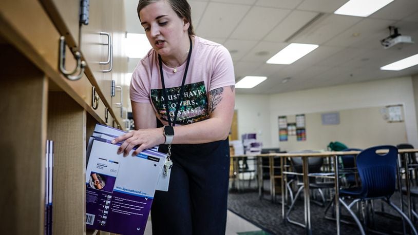 Amy Conrad, a first-year teacher for Dayton Public Schools, stacks books onto shelves Thursday, Aug. 10 in her classroom at E.J. Brown Middle School in preparation for the first day of school Monday. JIM NOELKER/STAFF