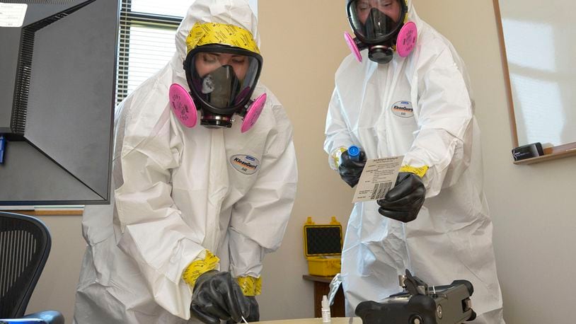 Senior Airman Abigail Pack (left) and Senior Airman Andrew Hutkowski collect a sample of an unknown powder for identification during a training exercise Sept. 17 at Wright-Patterson Air Force Base. The Bioenvironmental Engineering Flight trains regularly to swiftly respond to real-world events. U.S. AIR FORCE PHOTO/SENIOR AIRMAN EMILY RUPERT