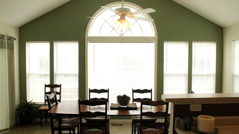 In the bright morning room a paddle fan centers the vaulted ceiling. A row of tall windows flank the extra-wide arched window at the center of the far wall.