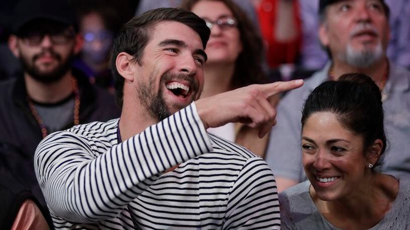 In this March 21, 2017, file photo, Michael Phelps and his wife, Nicole Johnson, smile during an NBA basketball game between the Los Angeles Lakers and the Los Angeles Clippers in Los Angeles. If Phelps returns to competitive swimming, the demands of training would surely cut heavily into his family time. That's why, if he tries to predict what the future might hold, it doesn't include a sixth Olympics at Tokyo in 2020. (AP Photo/Jae C. Hong, File)