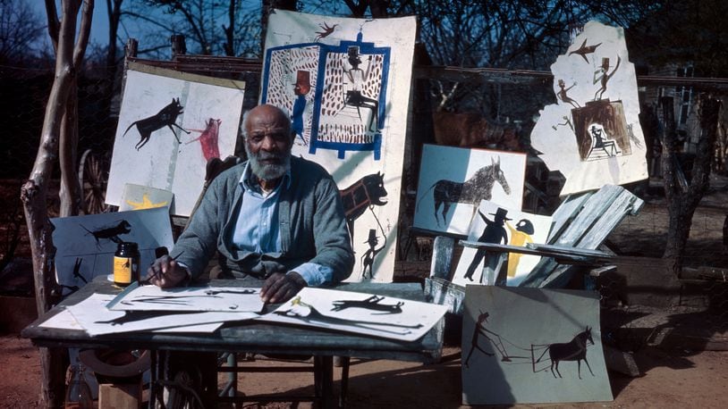Bill Traylor sits before a display of his artwork. CONTRIBUTED/PHOTO BY HORACE PERRY, COURTESY ALABAMA STATE COUNCIL ON THE ARTS