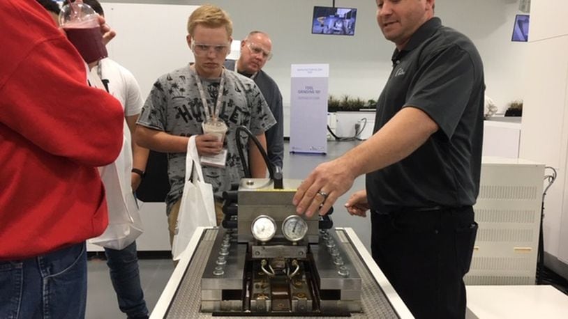 Jeff Gentile, right, a manufacturing services technician, explains his job at Miamisburg’s United Grinding North America to visiting students on Manufacturing Day Friday. THOMAS GNAU/STAFF