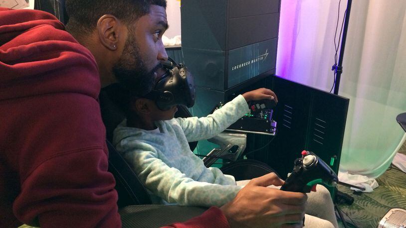Christopher Malaykhan helps his 9-year-old daughter Crystal pilot a helicopter in a simulator at Lockheed Martin’s display at Otronicon on Saturday, Jan. 13, 2018. (Marco Santana/Orlando Sentinel/TNS)