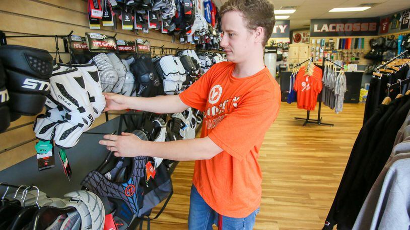 Tristian Burkhardt of Velocity Lacrosse, arranges items in the Voice of America Centre store, Thursday, May 11, 2017. GREG LYNCH / STAFF