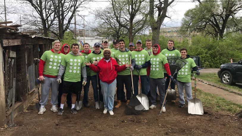 Annette Gibson-Strong is surrounded by the UD football players who helped clean up her Hopeland Street property and fix her home Saturday as part of the Rebuilding Together Dayton project in the Carillon Neighborhood near Welcome Stadium. Tom Archdeacon/STAFF