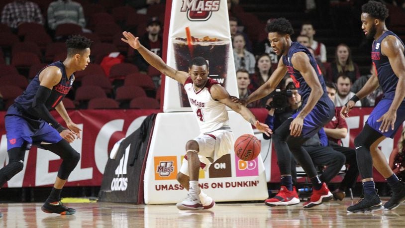 Dayton and Massachusetts eye a loose ball in the first half on Saturday, Feb. 3, 2018, at the Mullins Center in Amherst, Mass.