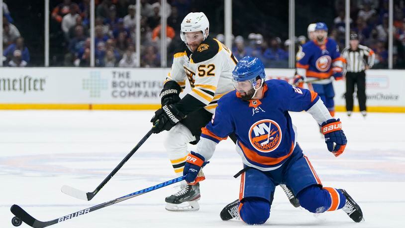 Boston Bruins' Sean Kuraly (52) and New York Islanders' Nick Leddy (2) reach for the puck during the third period of Game 3 during an NHL hockey second-round playoff series Thursday, June 3, 2021, in Uniondale, N.Y. (AP Photo/Frank Franklin II)