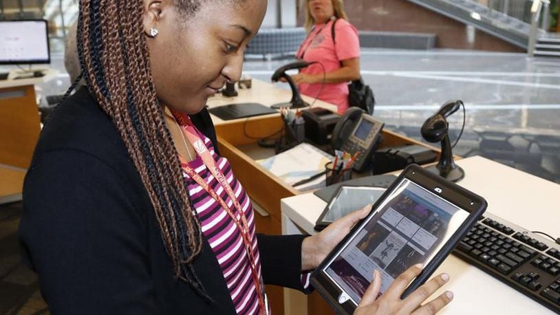 Dayton Metro Library services assistant Destinee Hamilton sets up an e-book reader at the main library on East Fifth Street in Dayton. Publishers have added new restrictions and raised the price for libraries who offer their materials which has resulted in fewer offerings from the library. TY GREENLEES/STAFF