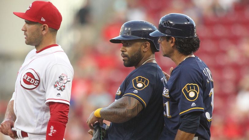 The Brewers Eric Thames, center, stands on first after reaching base against the Reds on Friday, June 29, 2018, at Great American Ball Park in Cincinnati. David Jablonski/Staff