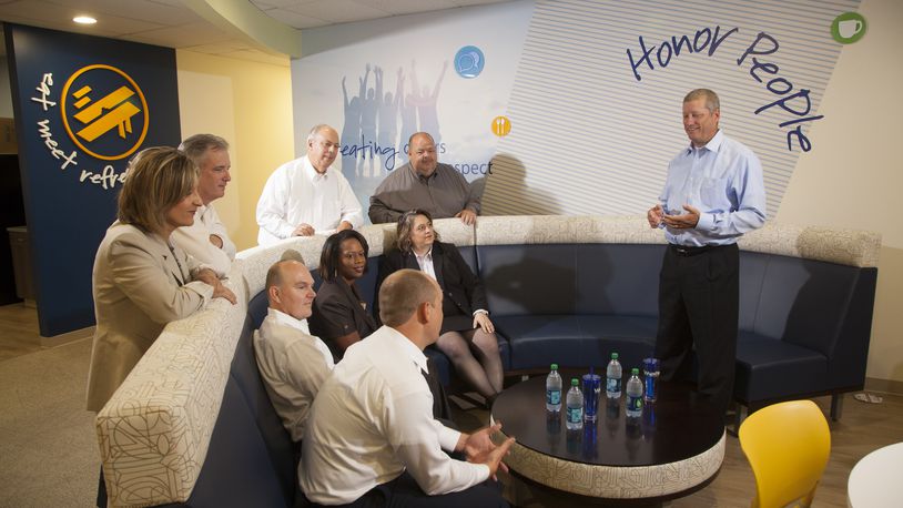 Doug Fecher, Wright-Patt Credit Union president and chief executive, right, holds a team meeting in in the cafe of Wright-Patt Credit Union’s headquarters at 3660 Pentagon Boulevard in 2014. TY GREENLEES / STAFF