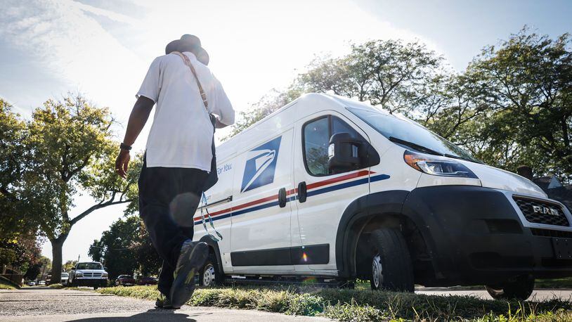 A mail carrier walks back to his truck after picking up and delivering mail on the eastside of Dayton. JIM NOELKER/STAFF