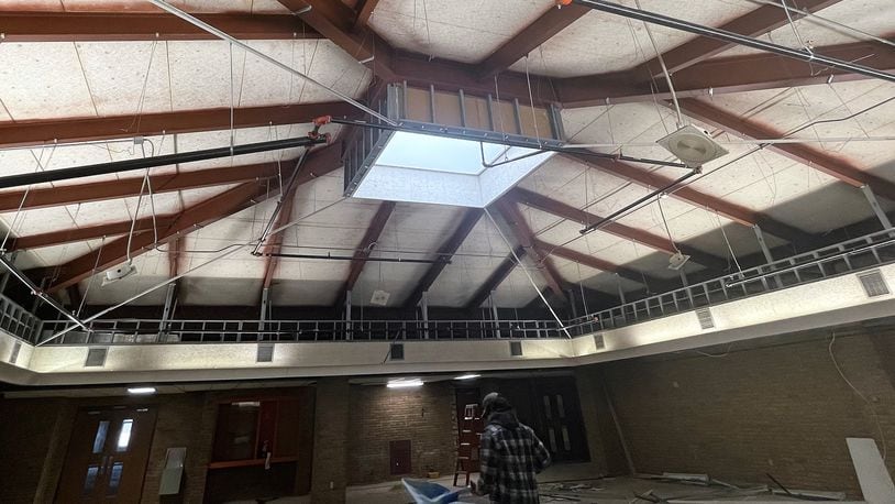Workers clear out materials below a stripped-out ceiling with a skylight, showing the inner workings of what's going into the construction project.