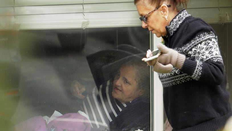 Carmen Gray, right, talks with her mother, Susan Hailey, left, who has tested positive for the new coronavirus, through the window of Hailey’s room at the Life Care Center in Kirkland, Wash., Tuesday, March 17, 2020, near Seattle. In-person visits are not allowed at the nursing home, at the center of the outbreak of new coronavirus. (AP Photo/Ted S. Warren)
