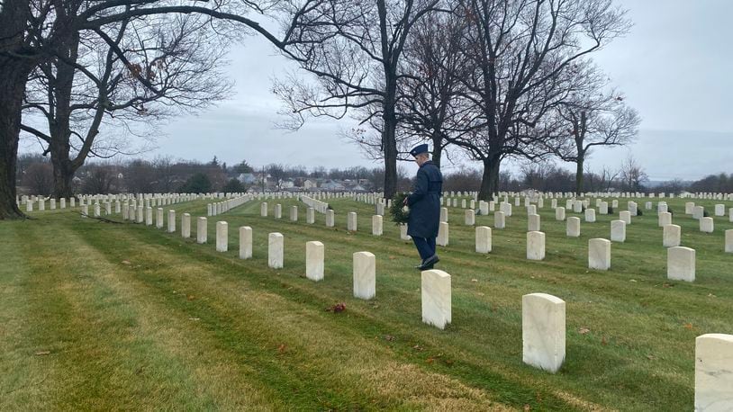 Owen Watkins, a member of the civil air patrol, holds a wreath and walks among the grave markers at Dayton National Cemetery on Saturday, Dec. 18. Eileen McClory / staff