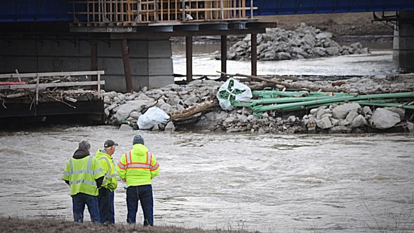 Workers watch the Great Miami River near the Keowee Street Bridge in February 2019 when a large water main break in the river cut water service to much of Montgomery County.  MARSHALL GORBY / STAFF