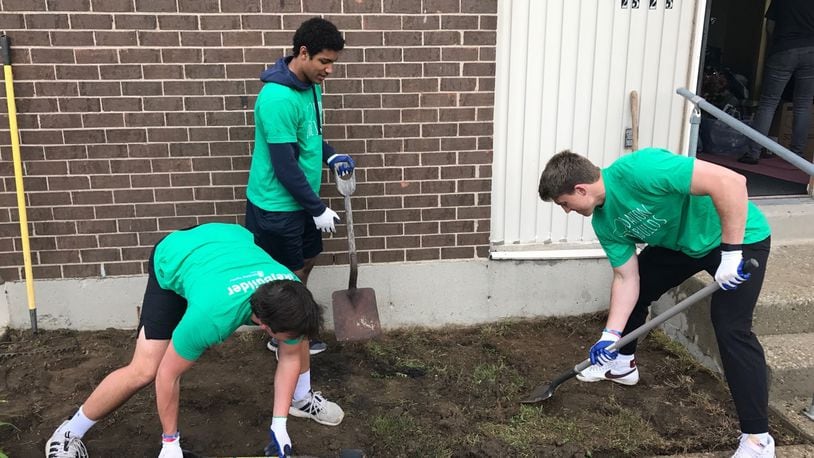 Dayton Flyers teammates (left to right) quarterback Ryan Van Schelven, wide receiver Kyle Hazell and quarterback Cole Dow put in a flower bed in front of Hazel Higgins’ home on Weaver Street Saturday as part of the Rebuild Together Dayton effort.  (Tom Archdeacon photo)