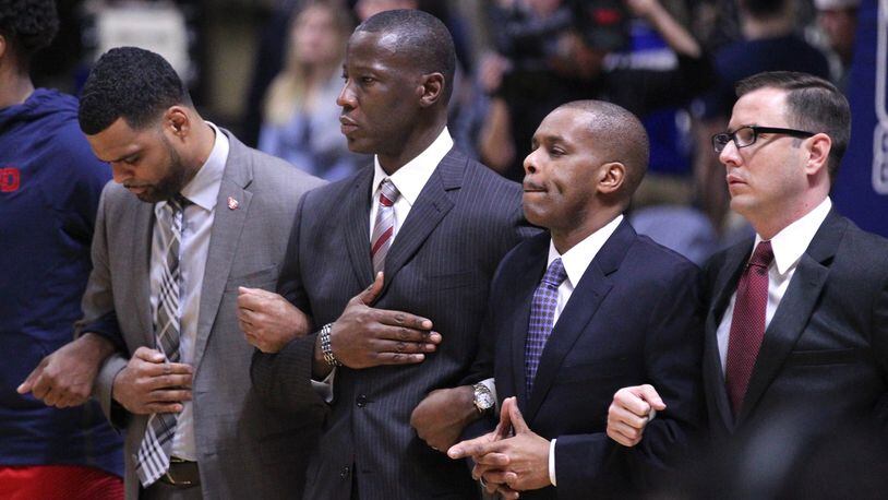 Dayton coaches (left to right) Ricardo Greer, Anthony Grant, Anthony Solomon and James Kane stand for the national anthem before a game against Rhode Island on Friday, Feb. 23, 2018, at the Ryan Center in Kingston, R.I. David Jablonski/Staff