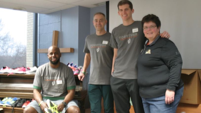 Wright State Raiders basketball assistant coach Sharif Chambliss (from left), head coach Scott Nagy, assistant coach Clint Sargent and Samaritan’s Feet regional director of operations Denise Blomberg at the Life Enrichment Center on Jan. 27. PAMELA DILLON/CONTRIBUTED