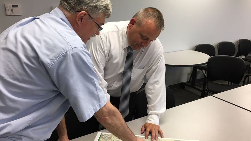 Ken LeBlanc (left), outgoing executive director of the Greene County Regional Planning and Coordinating Commission, goes over a zoning map of the county with the new executive director Devon Shoemaker on June 26, 2018. RICHARD WILSON/STAFF