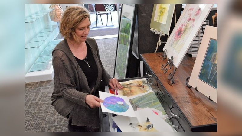 Artist Rusty Harden goes through some of her art work shortly after the opening of her new studio in downtown Tipp City. CONTRIBUTED
