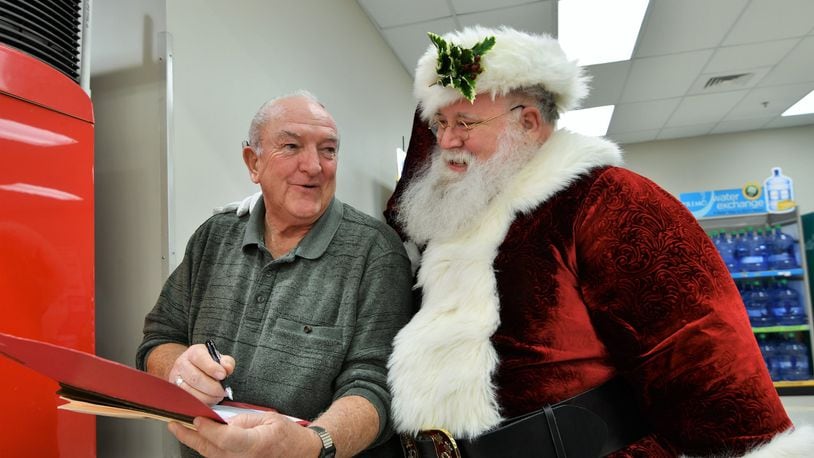 Billie Ray (left) and Santa check the list of families participating in this year’s COPS program in Miami County. CONTRIBUTED